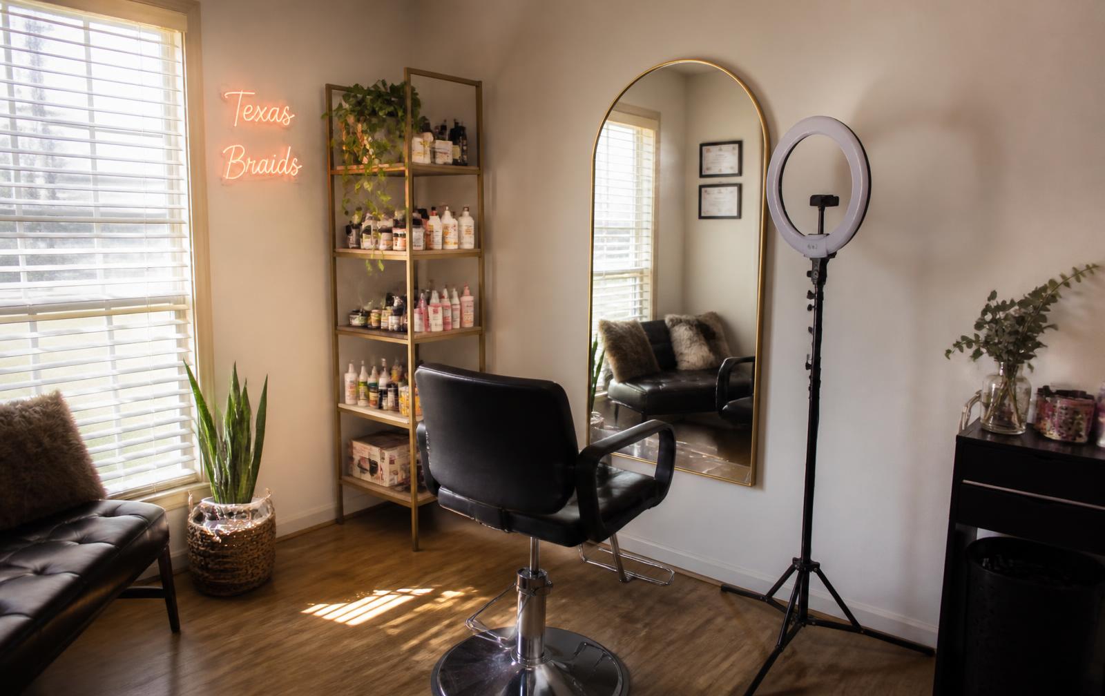 Private home braiding salon with a styling chair, arched mirror and warm natural light